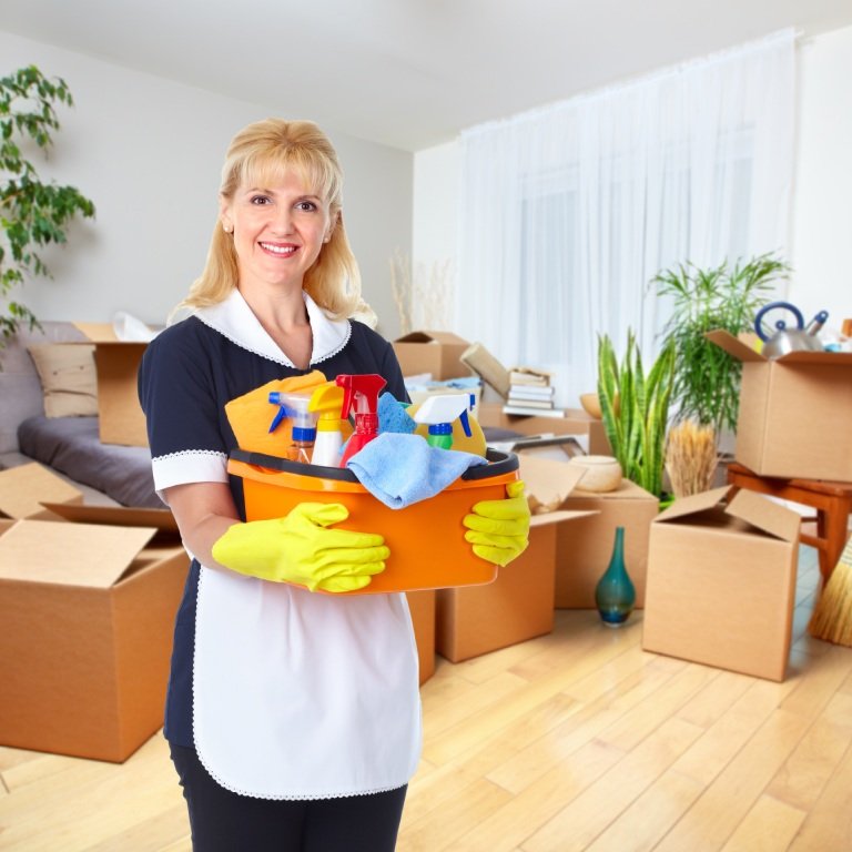 Khorasan GmbH - Reinigungsfachkraft mit Eimer voller Reinigungsmittel vor einem Haufen Kartons